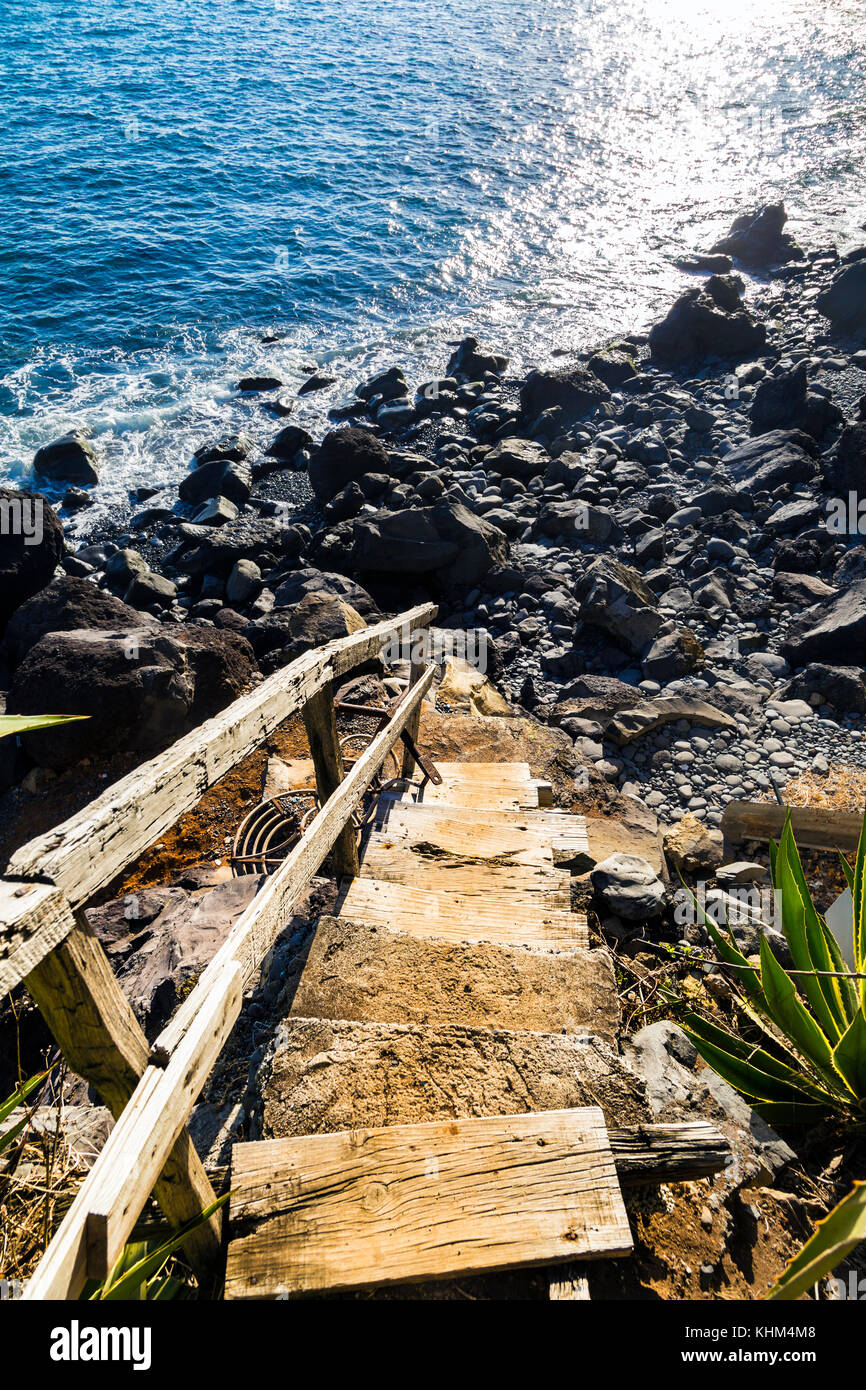 Alte hölzerne Treppe, die zu einem felsigen Strand vulkanischen Ursprungs in Funchal, Madeira, Portugal Stockfoto