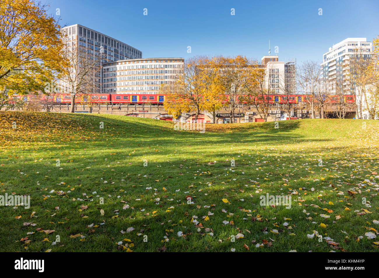 Vauxhall, London, Großbritannien, 17. November 2017; Herbst Szene im Vauxhall Gärten. Bäume mit gelben Blätter, ein Zug und Bürogebäuden. Stockfoto