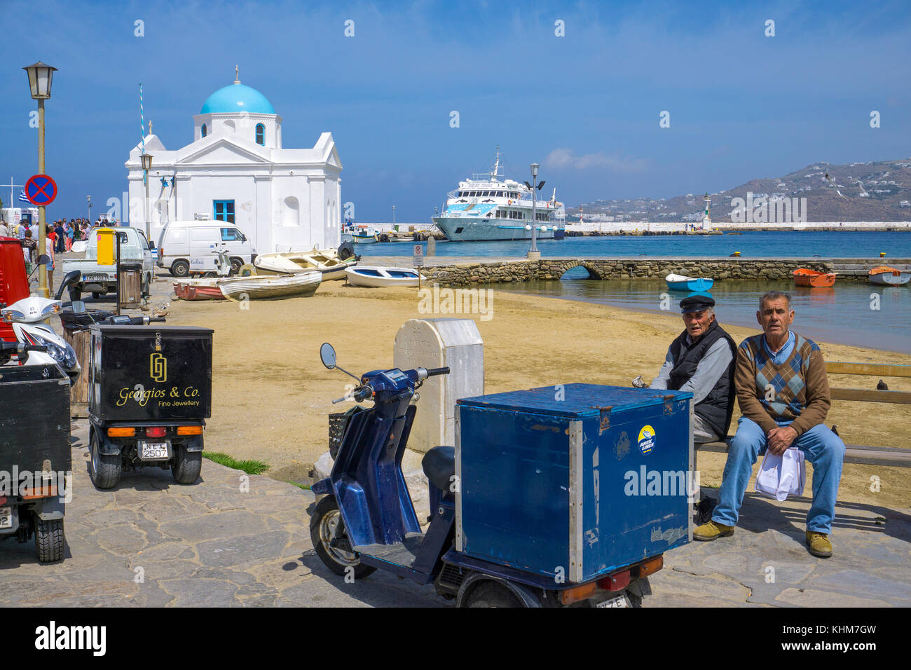 Einheimische mit Fracht Dreirädriges am Strand von Mykonos Stadt, Mykonos, Kykladen, Ägäis, Griechenland Stockfoto
