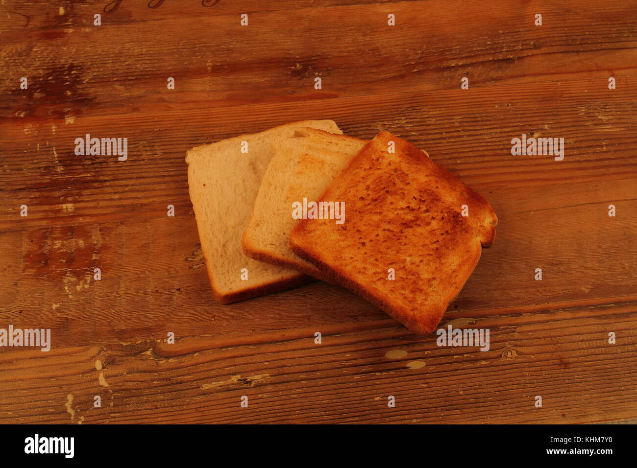 Drei Scheiben Toast, jeweils für einen längeren Zeitraum geröstet, auf der Oberfläche des Holzes im Querformat mit Kopie Raum Stockfoto