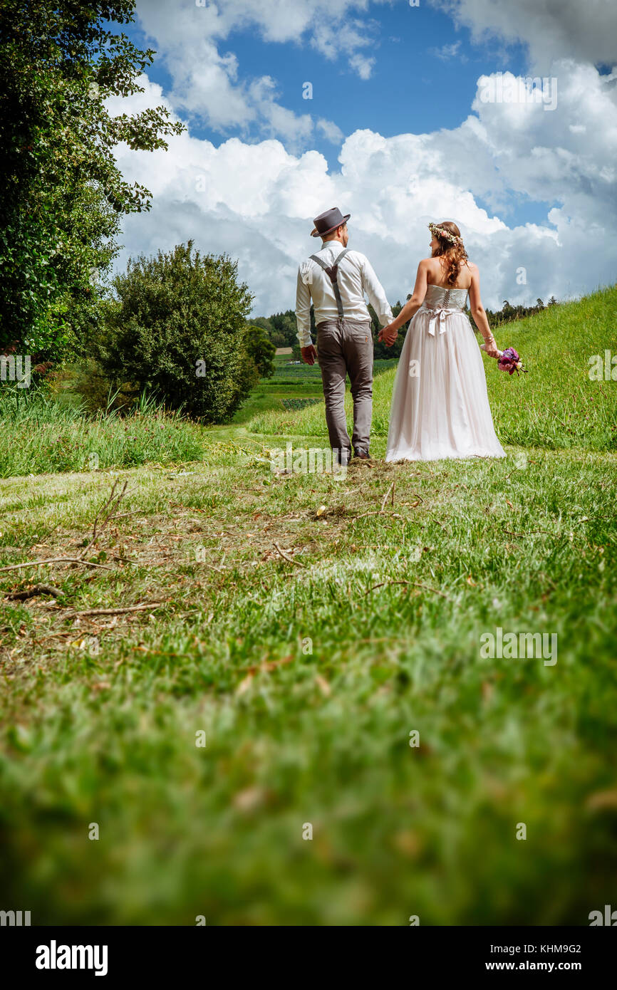 Foto eines Jungen jungvermählte Paar auf einen Weg durch einen Park halten sich an den Händen. Stockfoto