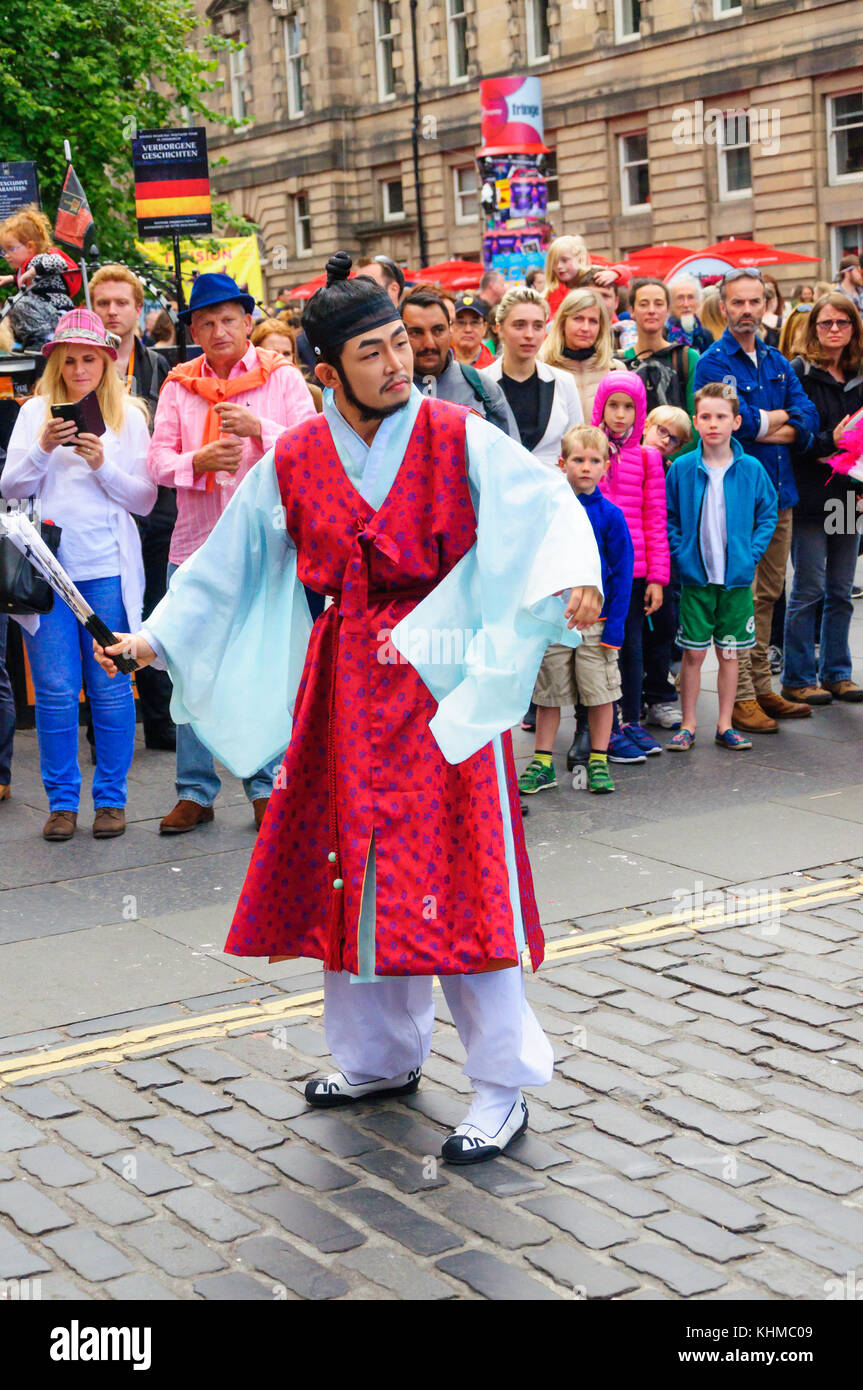Männliche Schauspieler ein Kostüm trägt und mit einem Ventilator ein Publikum auf der Royal Mile während des Edinburgh International Fringe Festival zu unterhalten Stockfoto