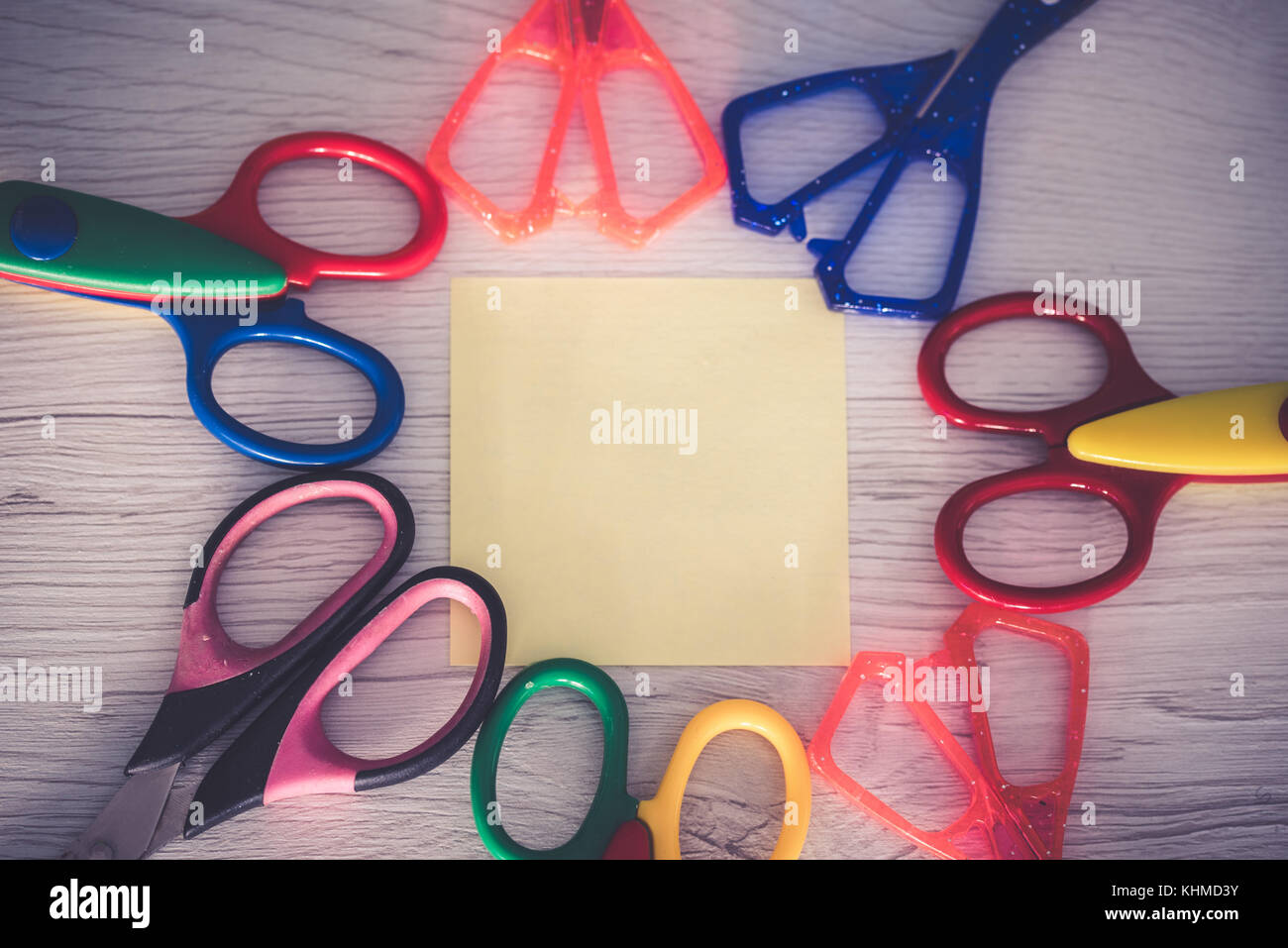 Bunte Schere mit einem Notizblock auf weißem Holz- Hintergrund. Stockfoto