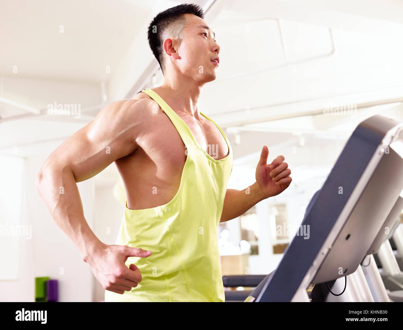 Asiatische Männlich Body Builder auf Laufband im Fitnessstudio, Seitenansicht. Stockfoto