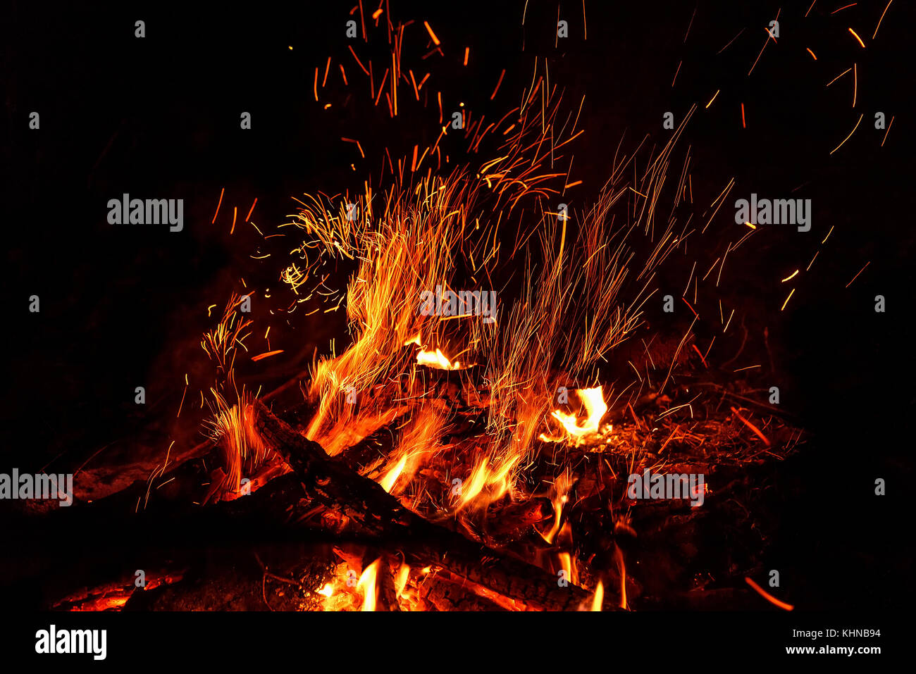 Rot und Orange Flammen der Scheiterhaufen und Funken in Form von Tracks auf schwarzem Hintergrund Stockfoto