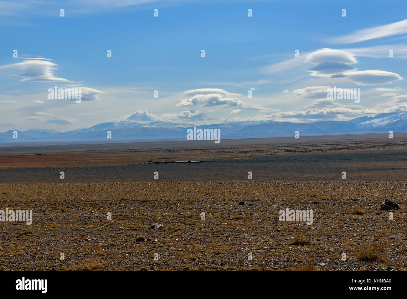 Die malerischen Steppe Herbst Landschaft mit Schnee in den Bergen, Steppen mit spärlicher Vegetation auf einem Hintergrund von blauen Himmel mit wunderschönen flauschigen abgedeckt Stockfoto