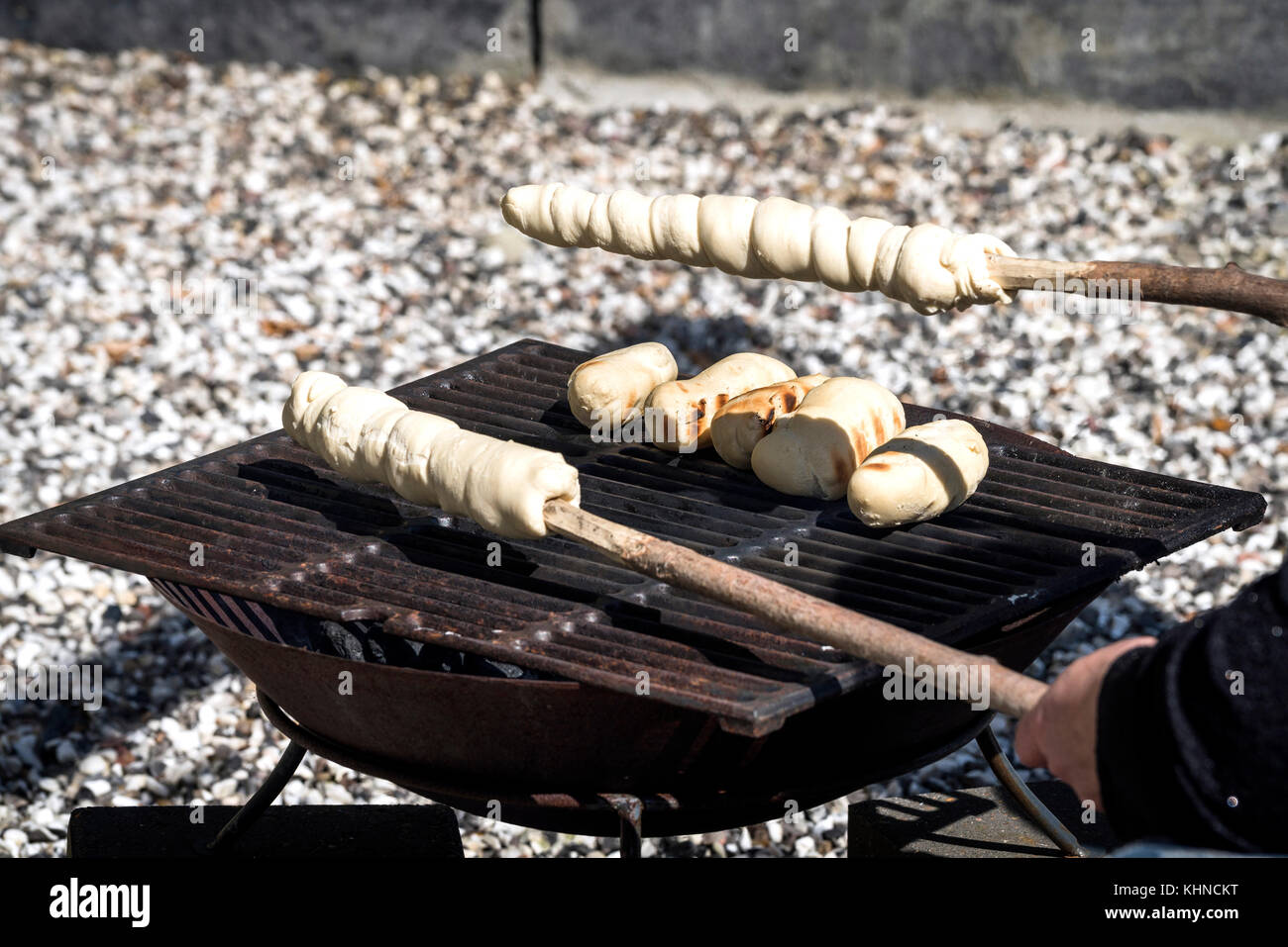 Brot auf einen Grill im Freien mit rohen Teig auf einem Stick fertig gebacken werden Stockfoto