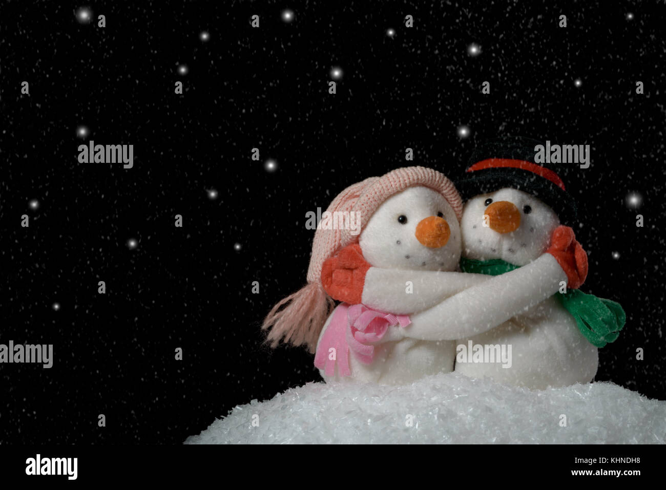 Umarmende Schneemänner Spielzeug auf dunklem Hintergrund Stockfoto