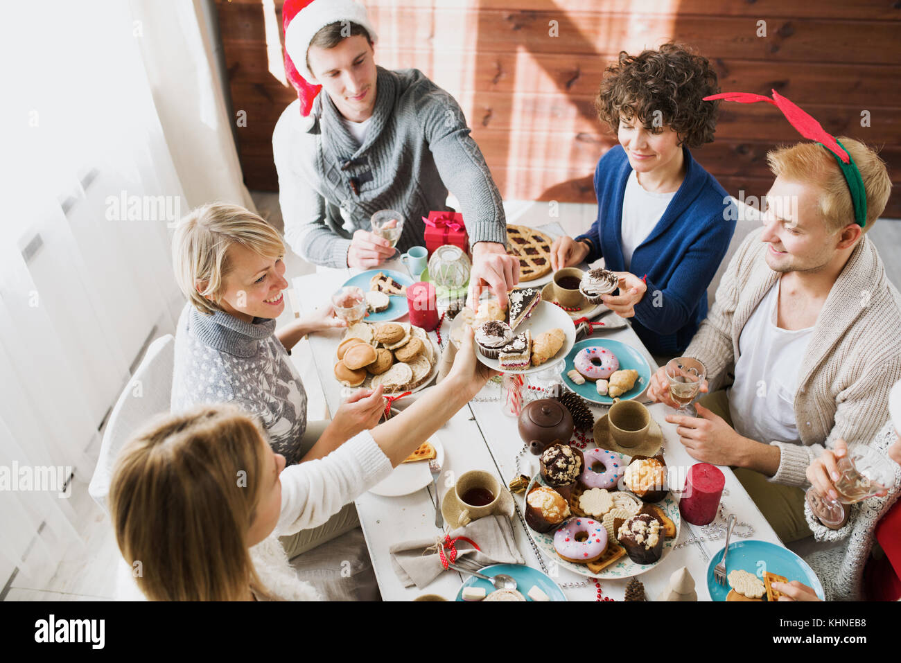 Mädchen geben ihren Gästen leckere hausgemachte Kuchen auf Platte während Weihnachten Abendessen Stockfoto