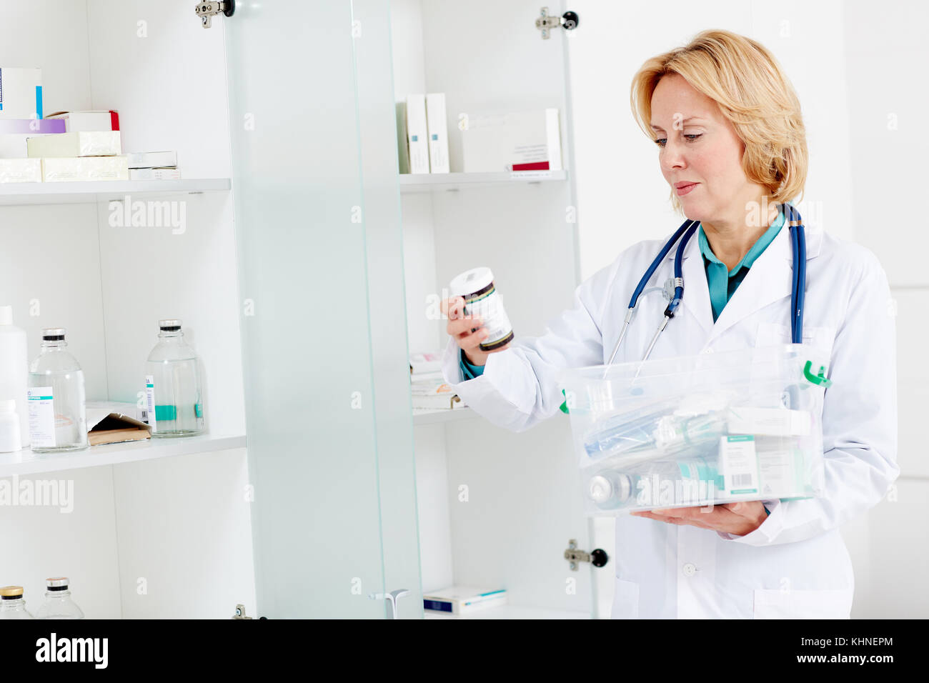 Ärztin suchen durch verschiedene Pille - Flaschen und andere Medizin aus Kunststoff Behälter Stockfoto