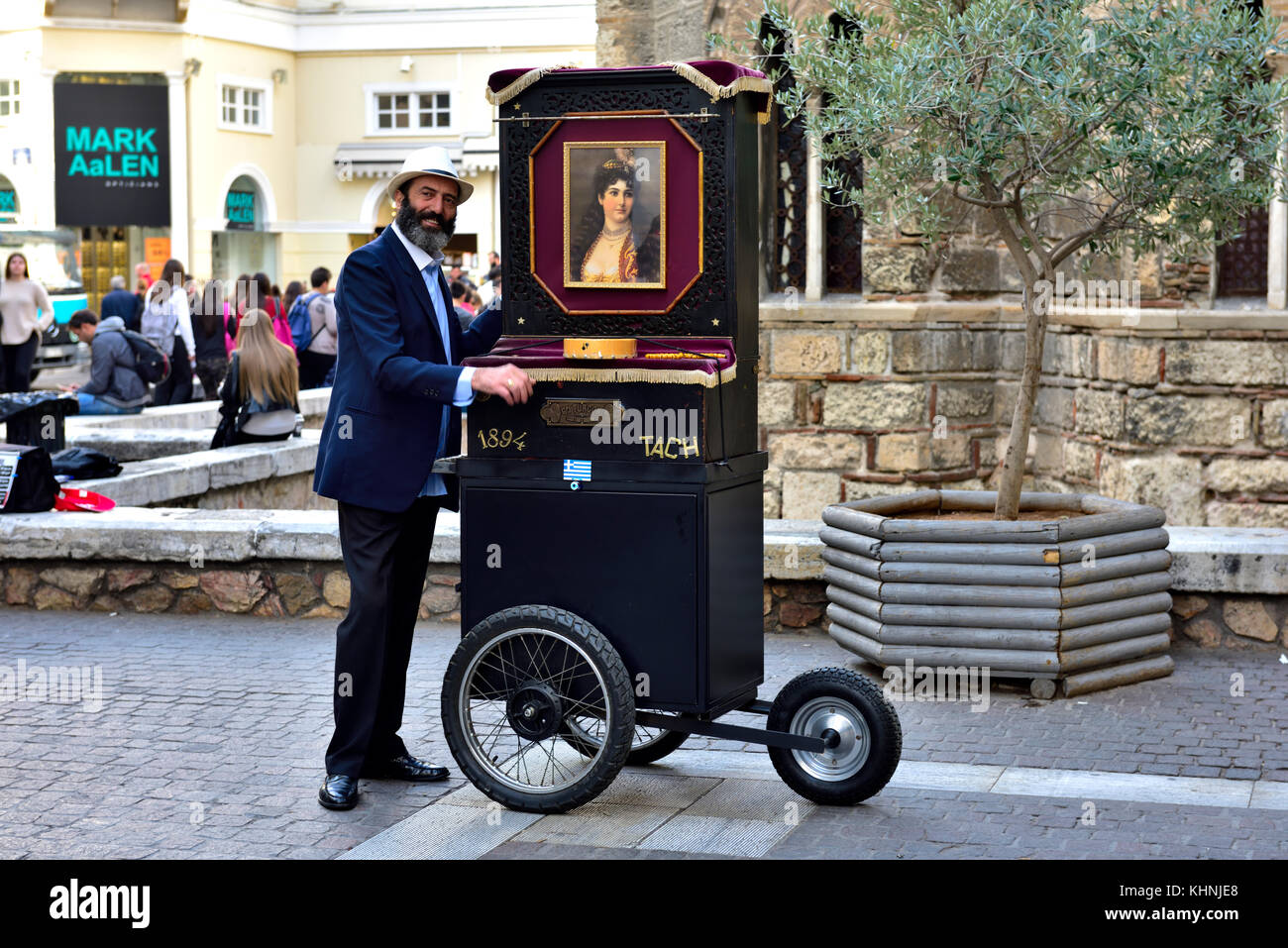 Straßenmusiker spielen eine Hand durchgedreht barrel Klavier oder laterna während Wheeling es entlang der Ermou Straße in Athen, Griechenland. Das barrel Klavier wurde fi Stockfoto