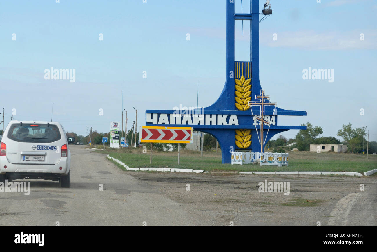 Straßenschild "chaplinka" und ein Auto der Mission der OSZE auf einer Straße. chaplinka Stadt in der Nähe der Grenzübergangsstelle chaplinka. khersonskaya Oblast, Ukraine Stockfoto