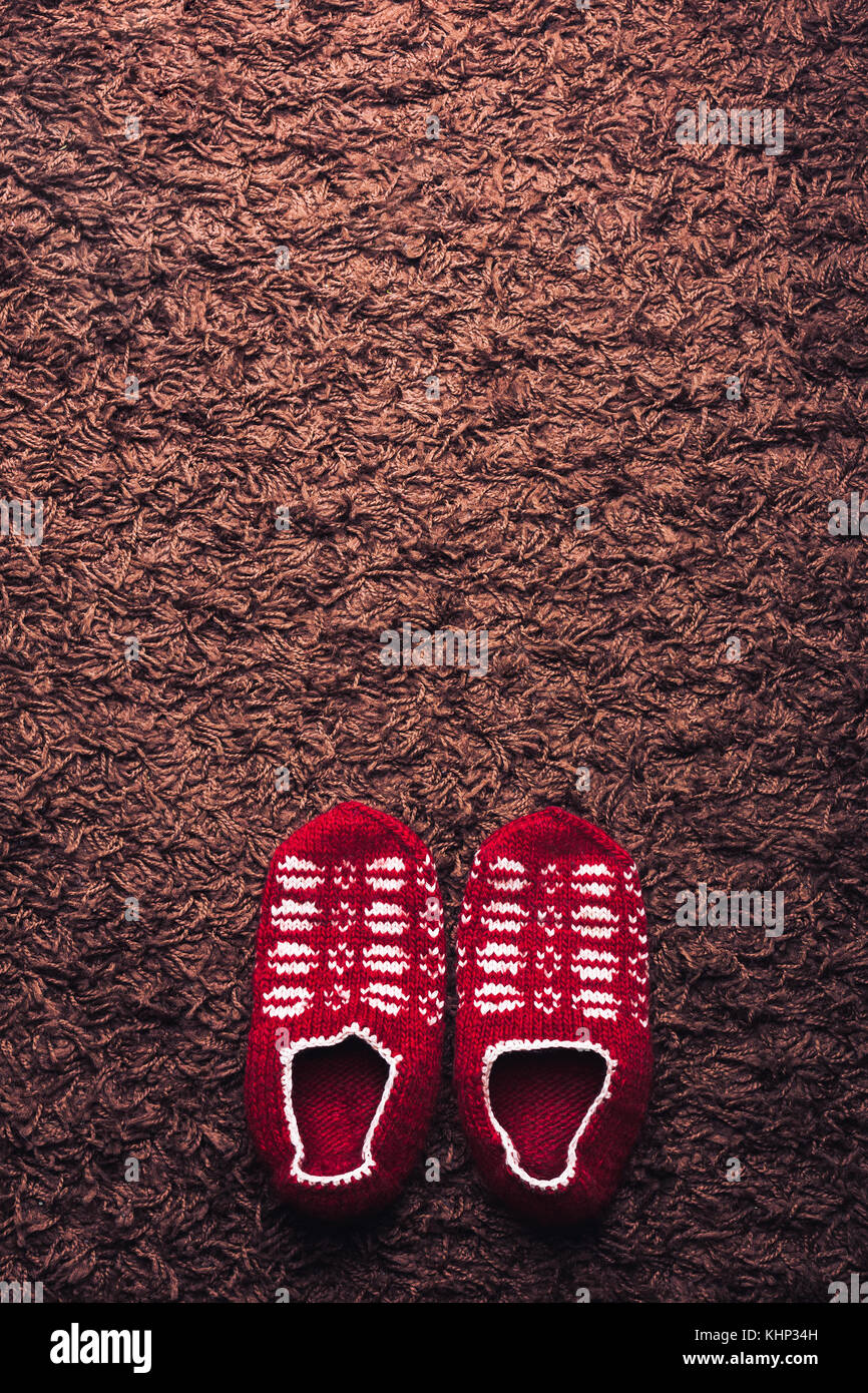 Füße tragen rot gemusterten Socken auf braunen Teppich Hintergrund. Komfort Konzept. Stockfoto