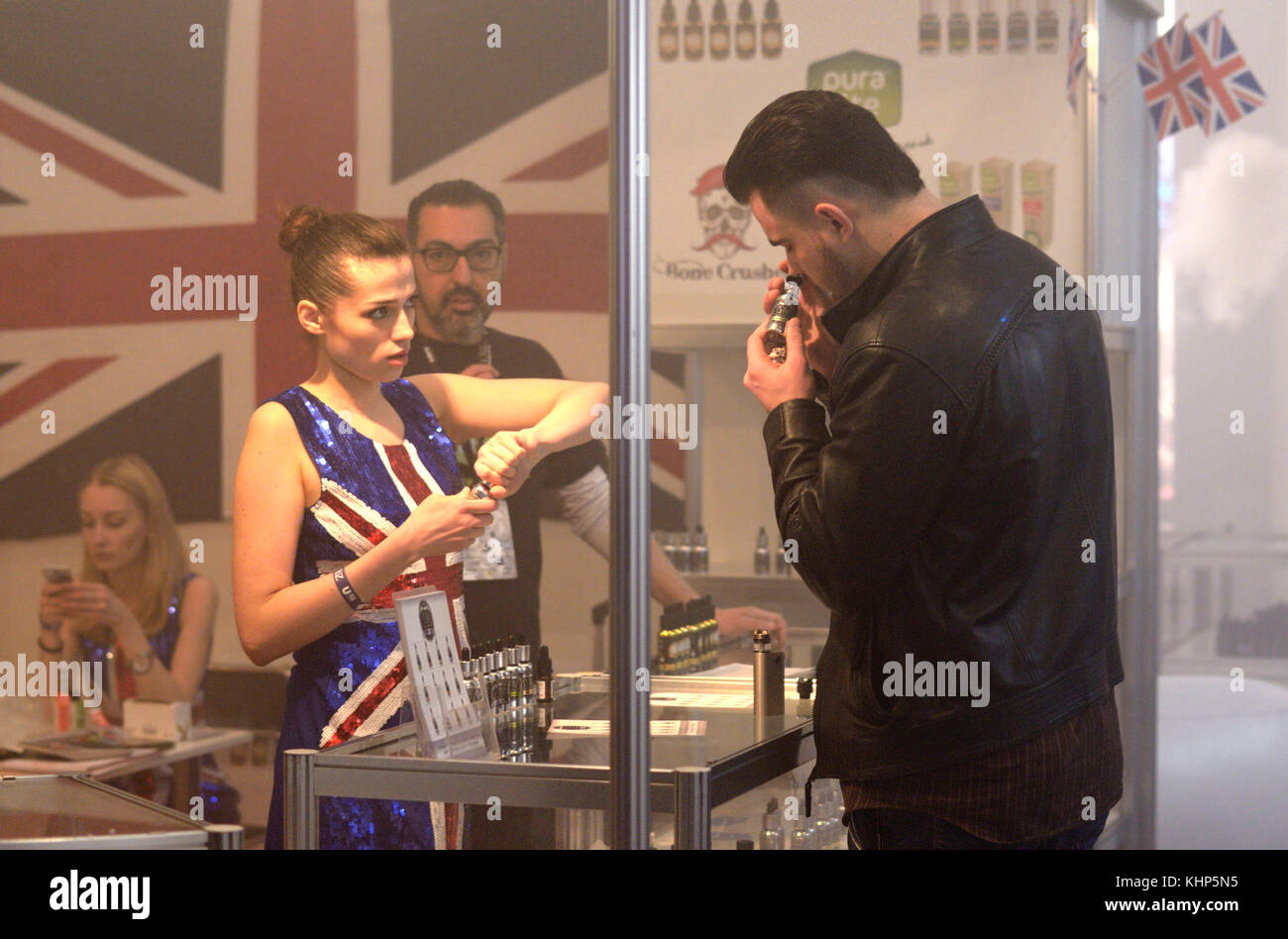 Mann riechen vape Geschmack aus einer Flasche und einem Mädchen gehen ihm ein anderes. vape & Expo. 19. März 2017 in Kiew, Ukraine zu geben Stockfoto