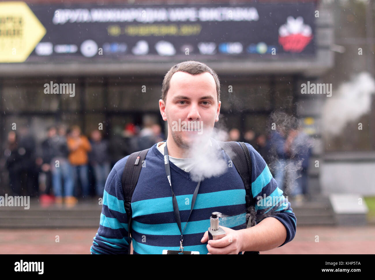 Junge, urbane Menschen rauchen vape vor unscharfen Menge von Menschen. vape & Expo an der Akko International Expo-Zentrum. Am 19. März 2017 in Kiew, Ukraine Stockfoto