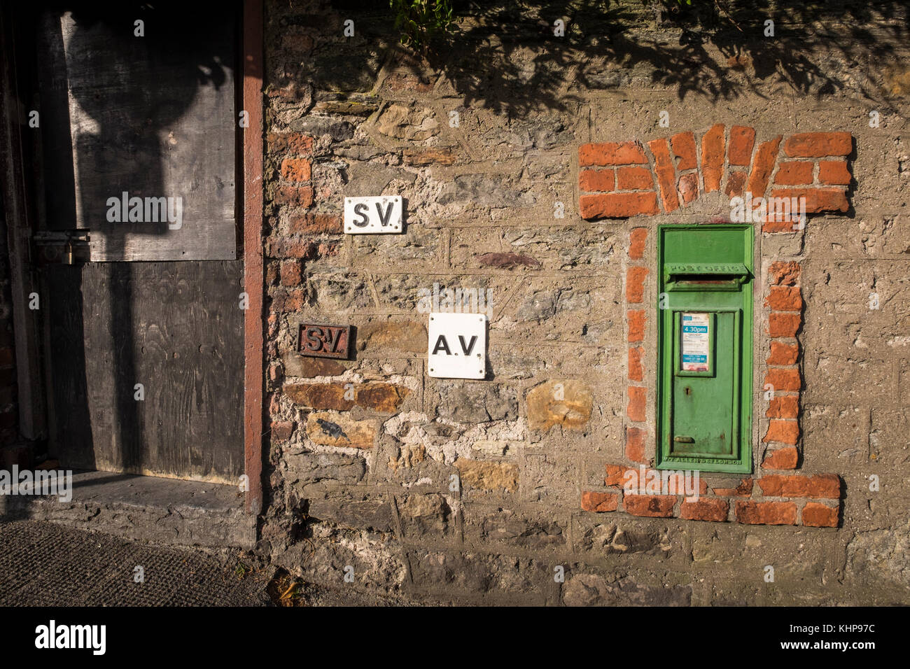 Grüne Post Box für den Versand von Briefen, in einem roten Backsteingebäude aus dem Rahmen in einer Mauer aus Stein mit SV und AV-metall Plaketten, Waterford, Irland Stockfoto