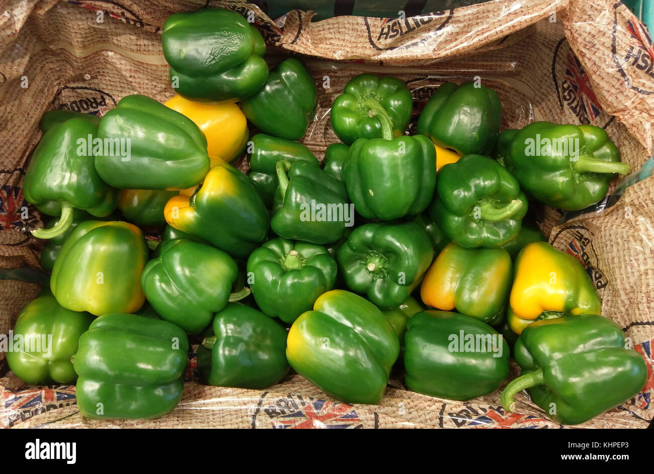 Grüne Paprika zum Verkauf in einem Laden mit einigen von Ihnen gerade erst gelb werden Stockfoto