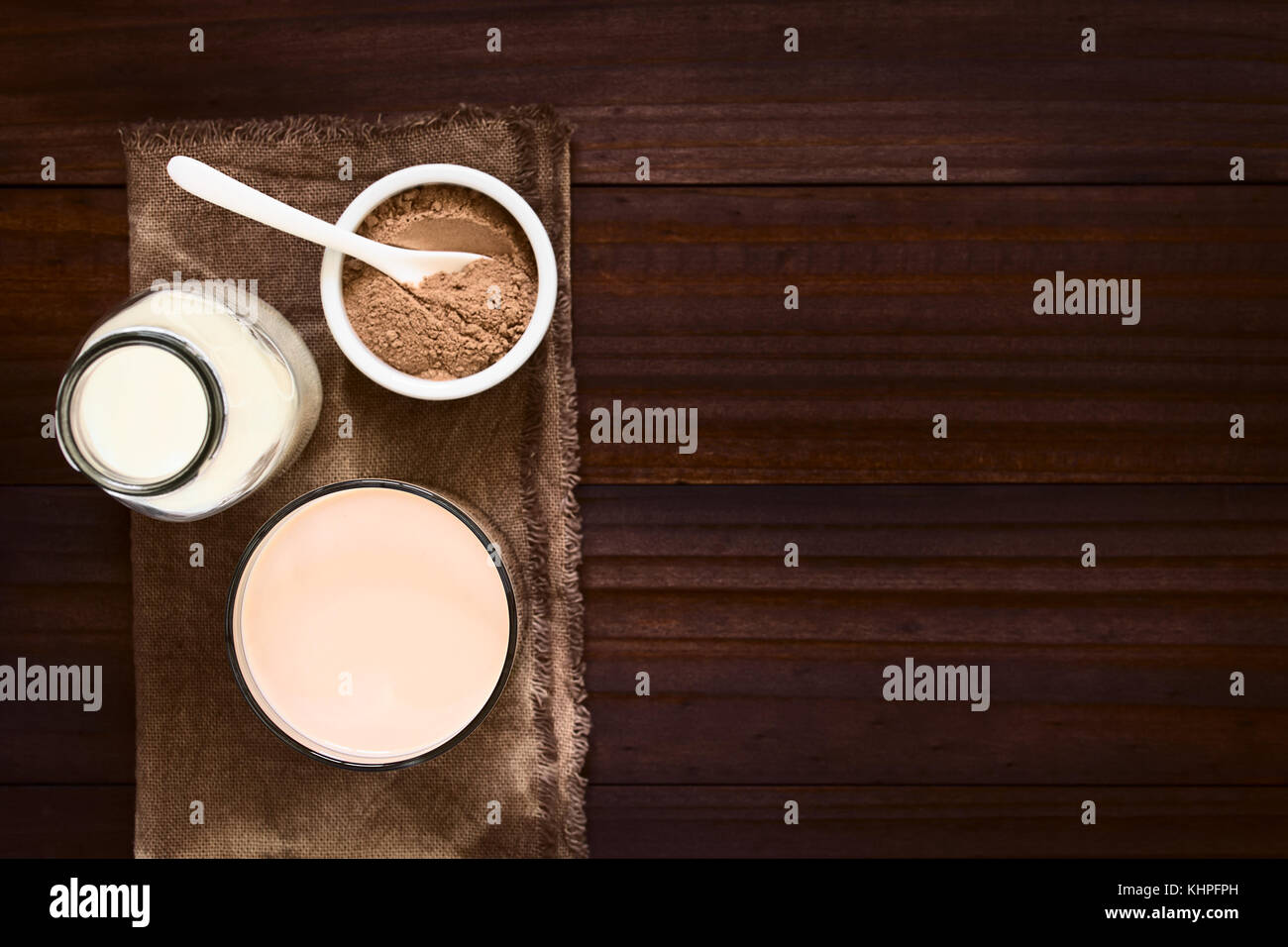 Schokolade Milch trinken in Glas, Flasche Milch und Schokolade oder Kakaopulver auf der Seite, Overhead fotografiert mit Tageslicht (selektive Fokus) Stockfoto