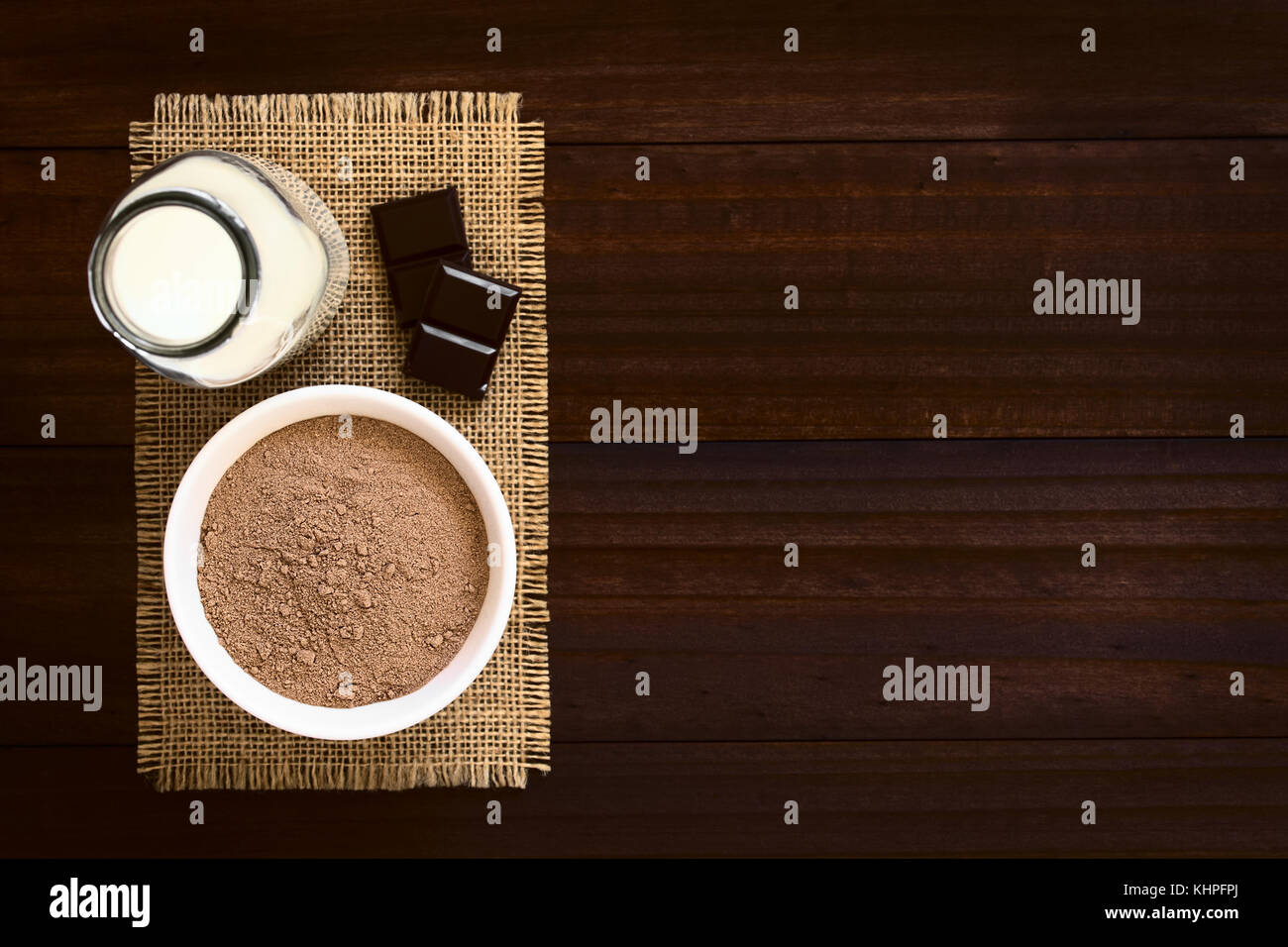 Kakao oder Schokolade Drink Pulver in der Schüssel mit einer Flasche Milch auf der Seite, Overhead fotografiert mit Tageslicht (selektive Fokus) Stockfoto
