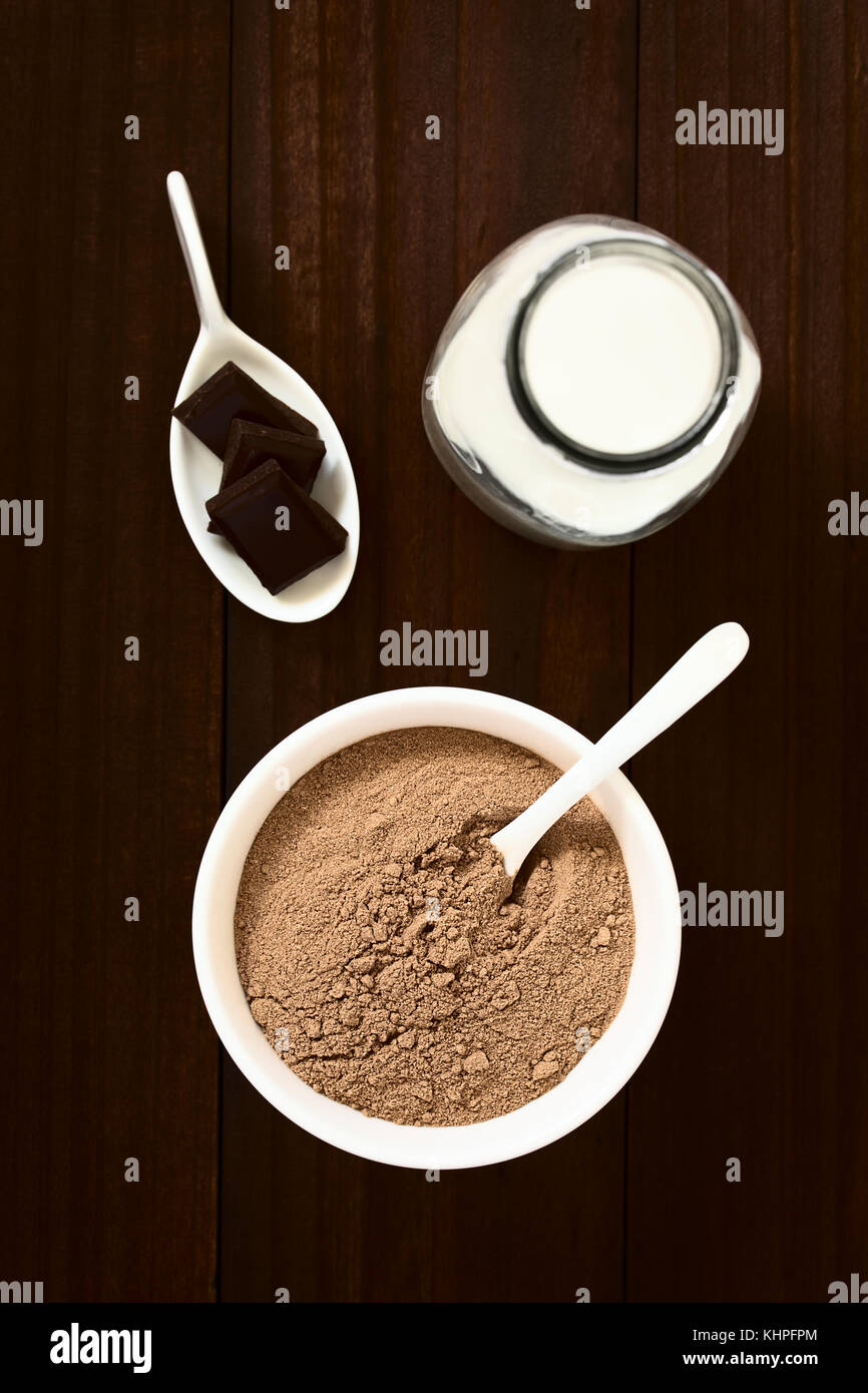 Kakao oder Schokolade Drink Pulver in der Schüssel mit einer Flasche Milch auf der Seite, Overhead fotografiert mit Tageslicht (selektive Fokus) Stockfoto