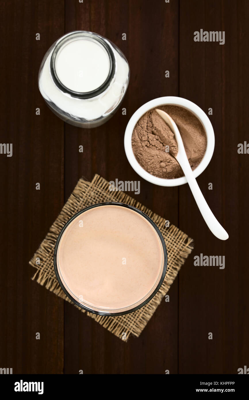 Schokolade Milch trinken in Glas, Flasche Milch und Schokolade oder Kakaopulver auf der Seite, Overhead fotografiert mit Tageslicht (selektive Fokus) Stockfoto
