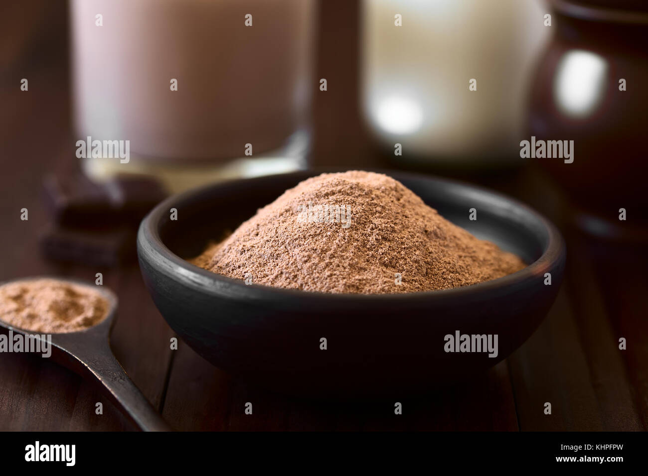 Kakao oder Schokolade Drink Pulver im rustikalen Schüssel, Schokolade und Milch in den Rücken, fotografiert mit Tageslicht (selektive Fokus) Stockfoto