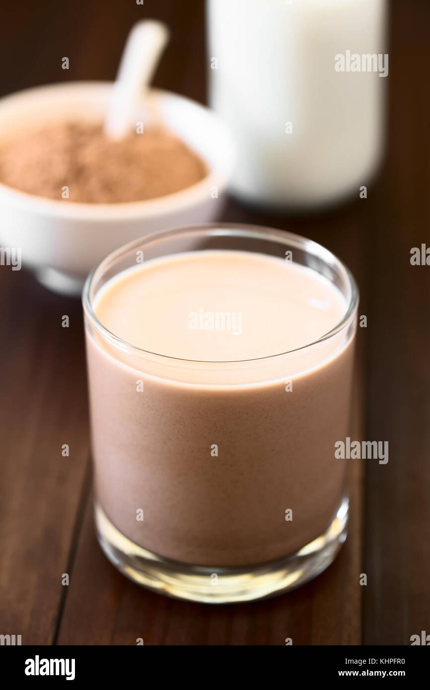 Schokolade Milch trinken in Glas, Schokolade oder Kakaopulver und Milch in den Rücken, fotografiert mit Tageslicht (selektive Fokus) Stockfoto
