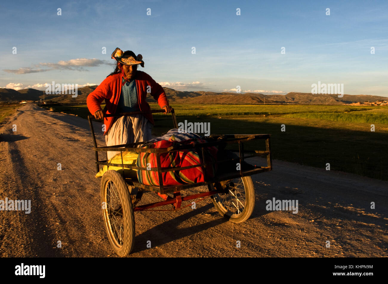 Eine Frau fährt mit ihrem Dreirad eine peruanische Hochlandstraße unweit von Juliaca, Puno, Peru. Stockfoto