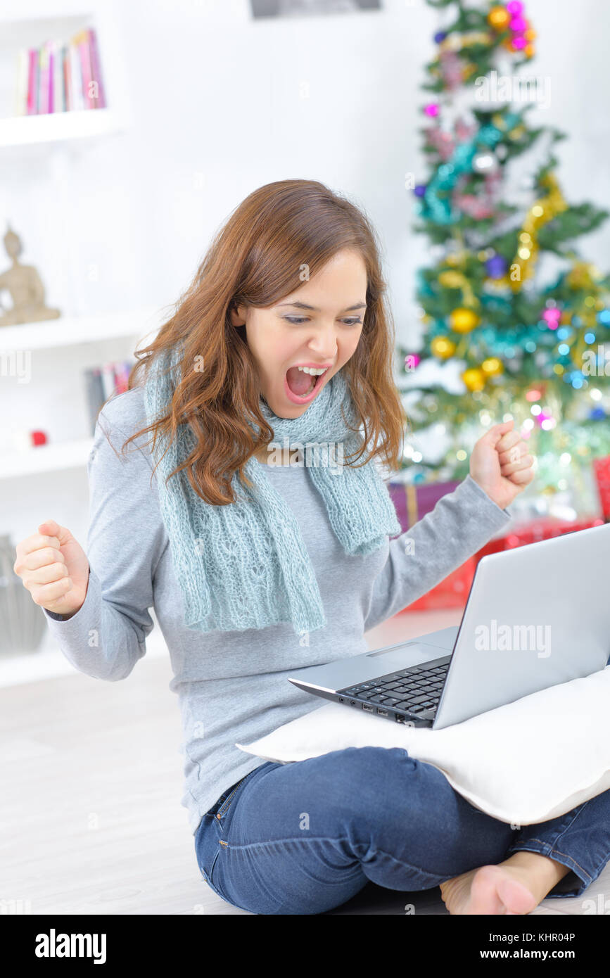 Junge Frau mit Laptop und Weihnachtsbaum Hintergrund Stockfoto