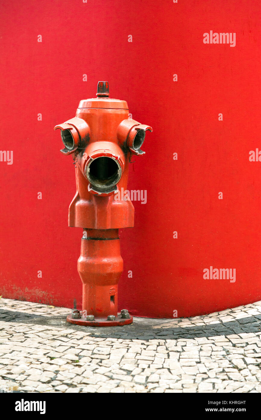 Red Fire Hydrant gegen eine Rote Wand in Funchal, Madeira, Portugal Stockfoto