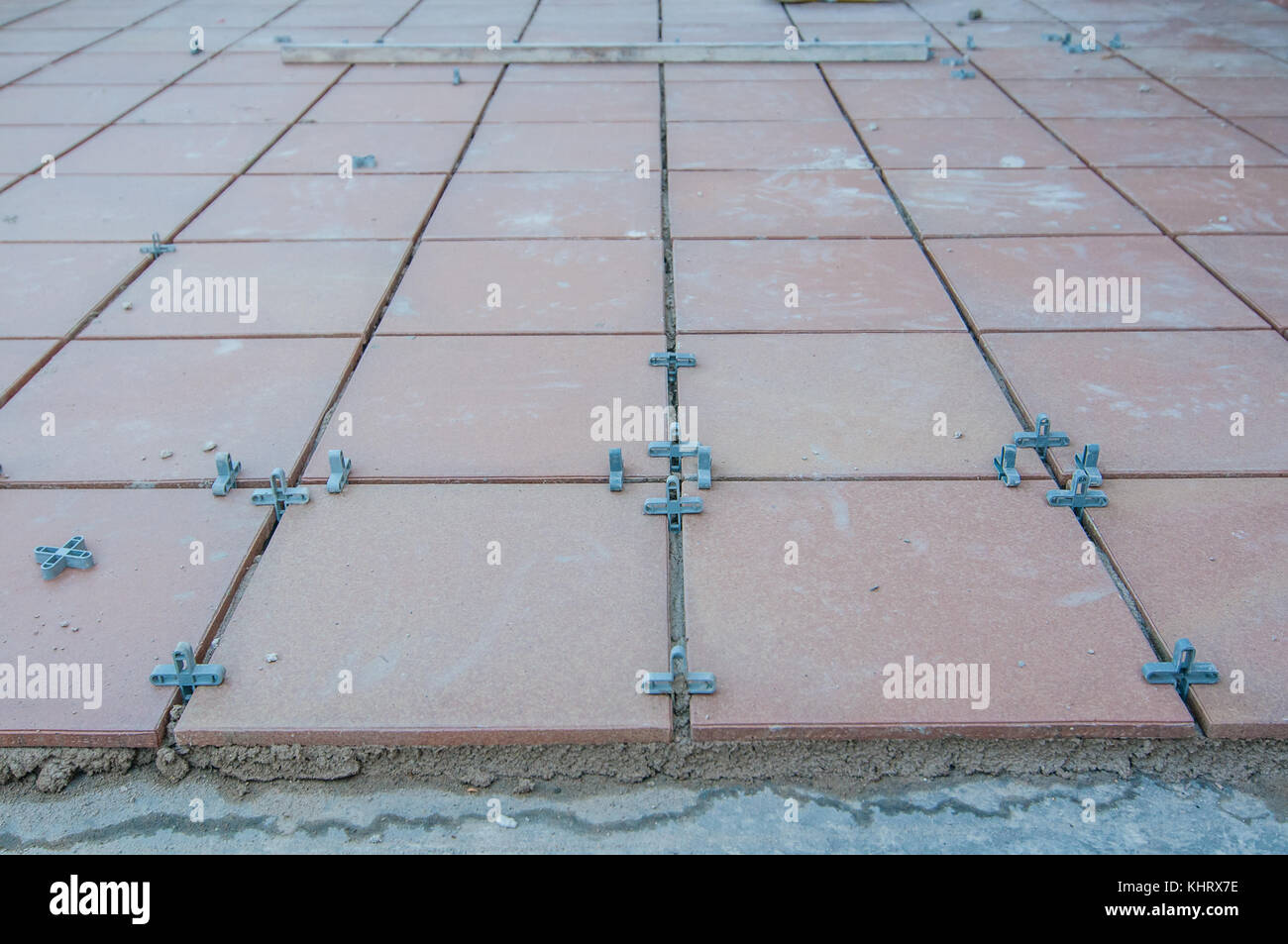 Installation von Fliesen auf der Terrasse Etage und einige Stücke aus Kunststoff mit Kreuz Form Raum zwischen den Fliesen zu lassen Stockfoto