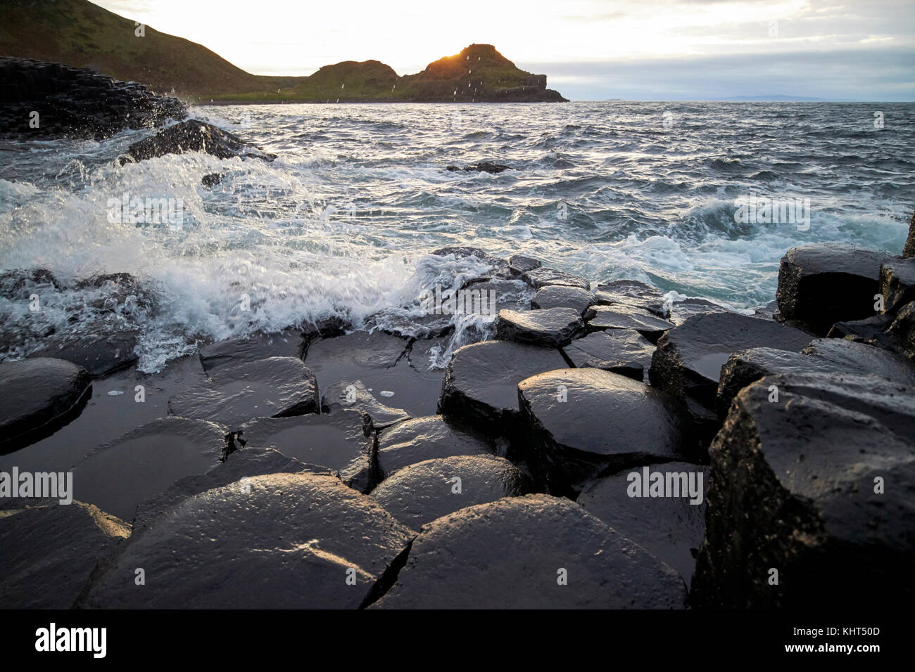 Wellen über Felsen brechen Sonnenuntergang Abend am Giants Causeway County Antrim Nordirland uk Stockfoto