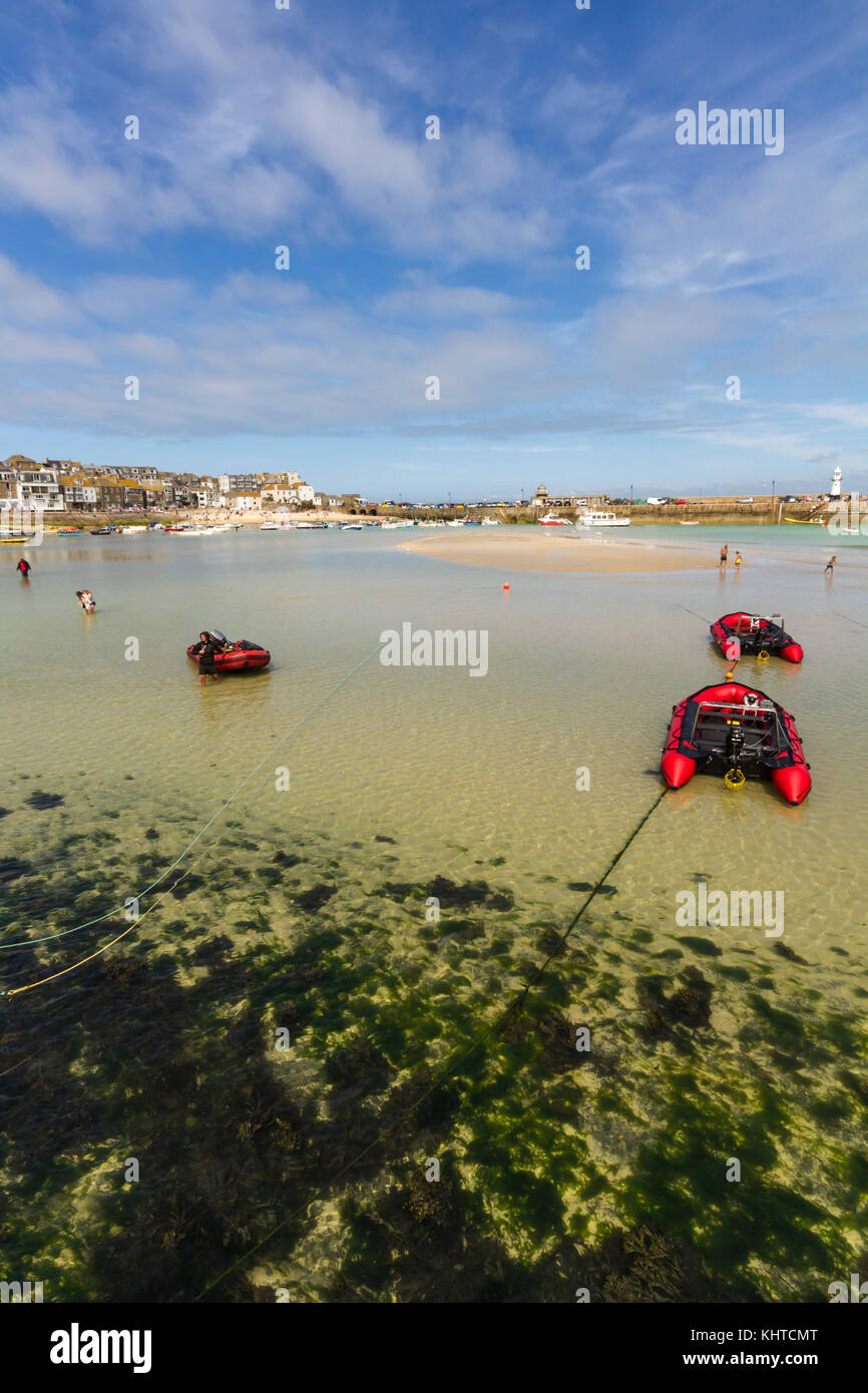 Blick auf die Bucht von St Ives bei Ebbe mit geerdetem Boote und Menschen Paddeln in das klare Wasser. Stockfoto