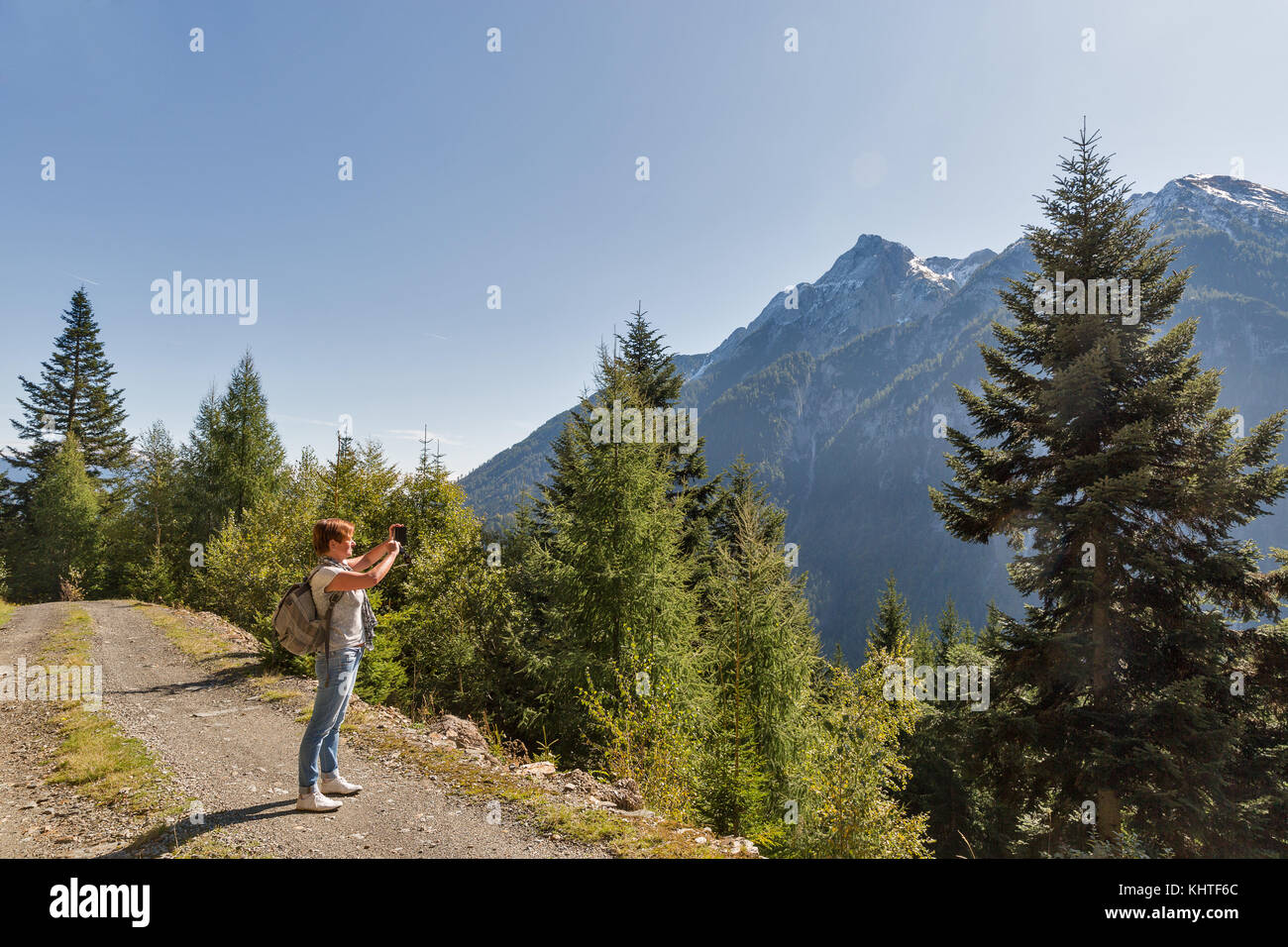 Frau macht smart phone Fotos von der alpinen Landschaft im westlichen Kärnten, Österreich. Stockfoto