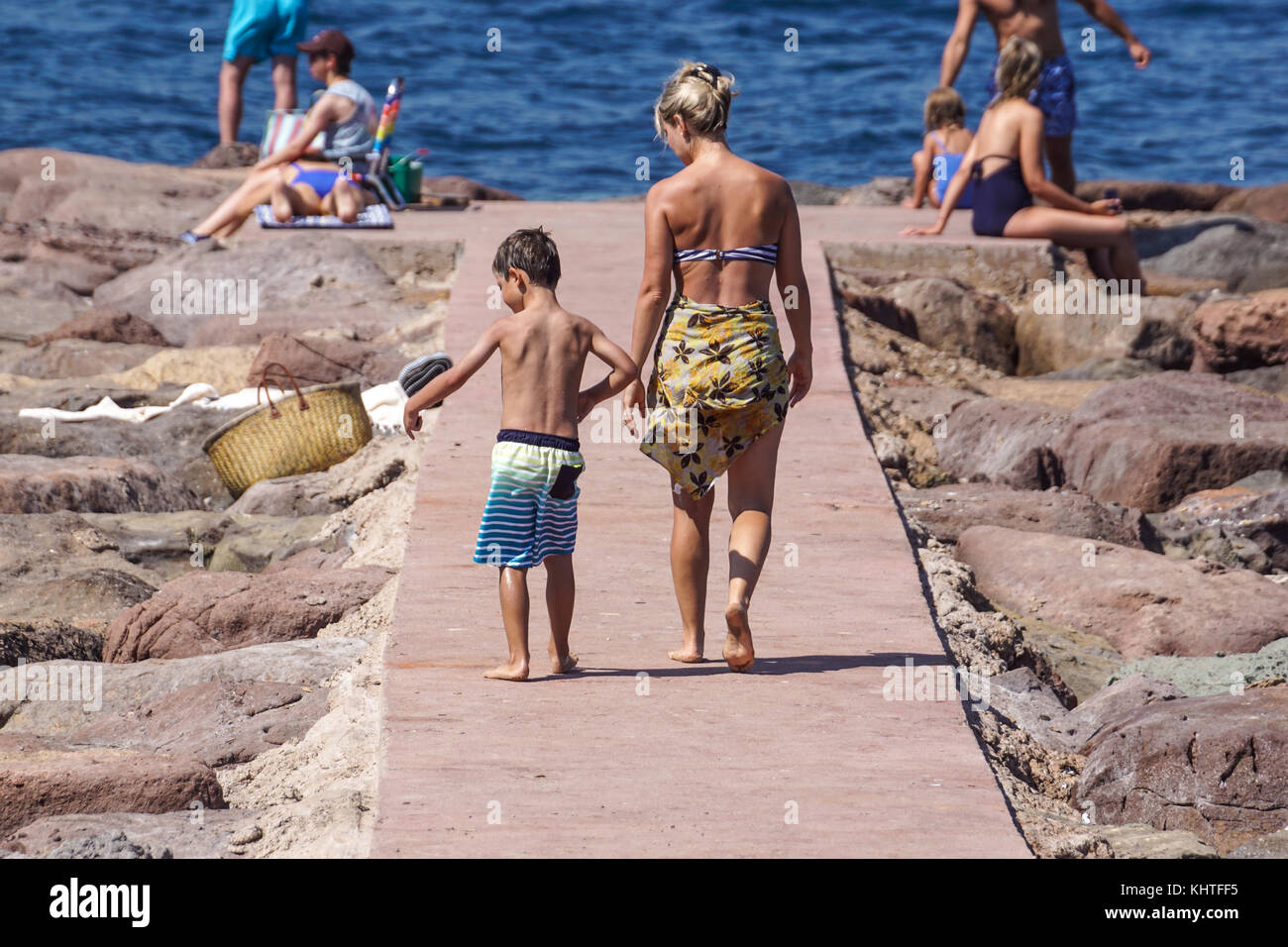 Nizza Frankreich, 15. August 2017: Rückansicht von Mather und Kind zu Fuß auf den felsigen Dock am Meer an einem heißen Sommertag Stockfoto