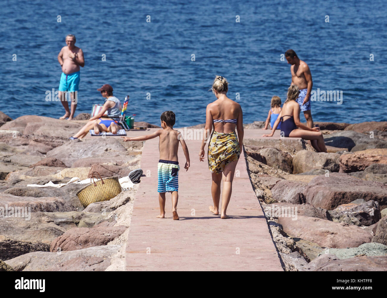 Nizza Frankreich, 15. August 2017: Rückansicht von Mather und Kind zu Fuß auf den felsigen Dock am Meer an einem heißen Sommertag Stockfoto
