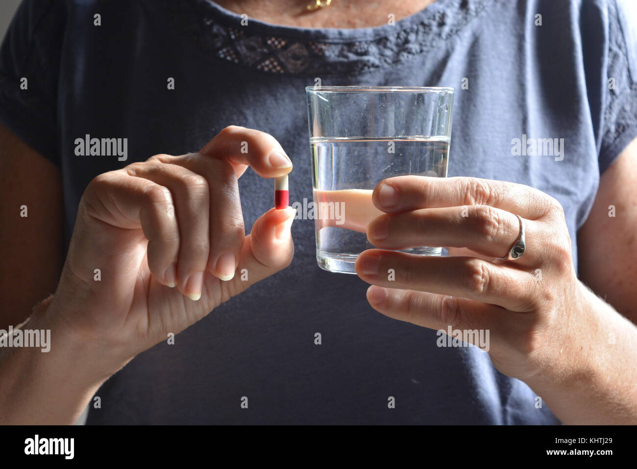Gesundheitswesen & Arzneimittel. Frau mit einem Gel Kapsel mit einem Glas Wasser. Stockfoto