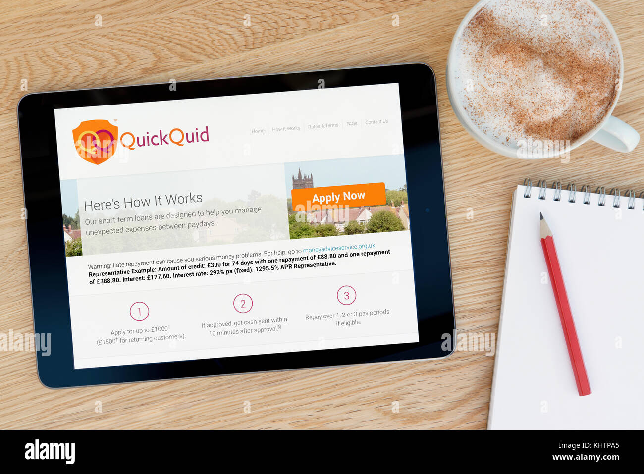 Die QuickQuid website Funktionen auf einem iPad Tablet Gerät, das auf einem Tisch liegt neben einem Notizblock und Bleistift und eine Tasse Kaffee (nur redaktionell) Stockfoto