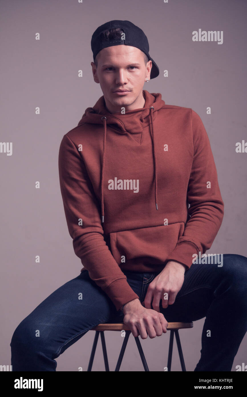 Ein junger Mann, Anfang 20, jungenhaft aussieht, im Studio posiert, legere Kleidung, Sweatshirt, cap, obere Körper geschossen Portrait Stockfoto