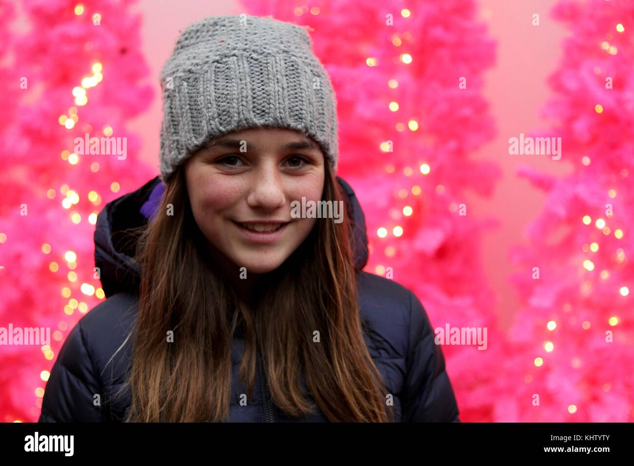 Junge Teenager Mädchen lächelnd vor einem rosa Hintergrund mit Beleuchtung Stockfoto