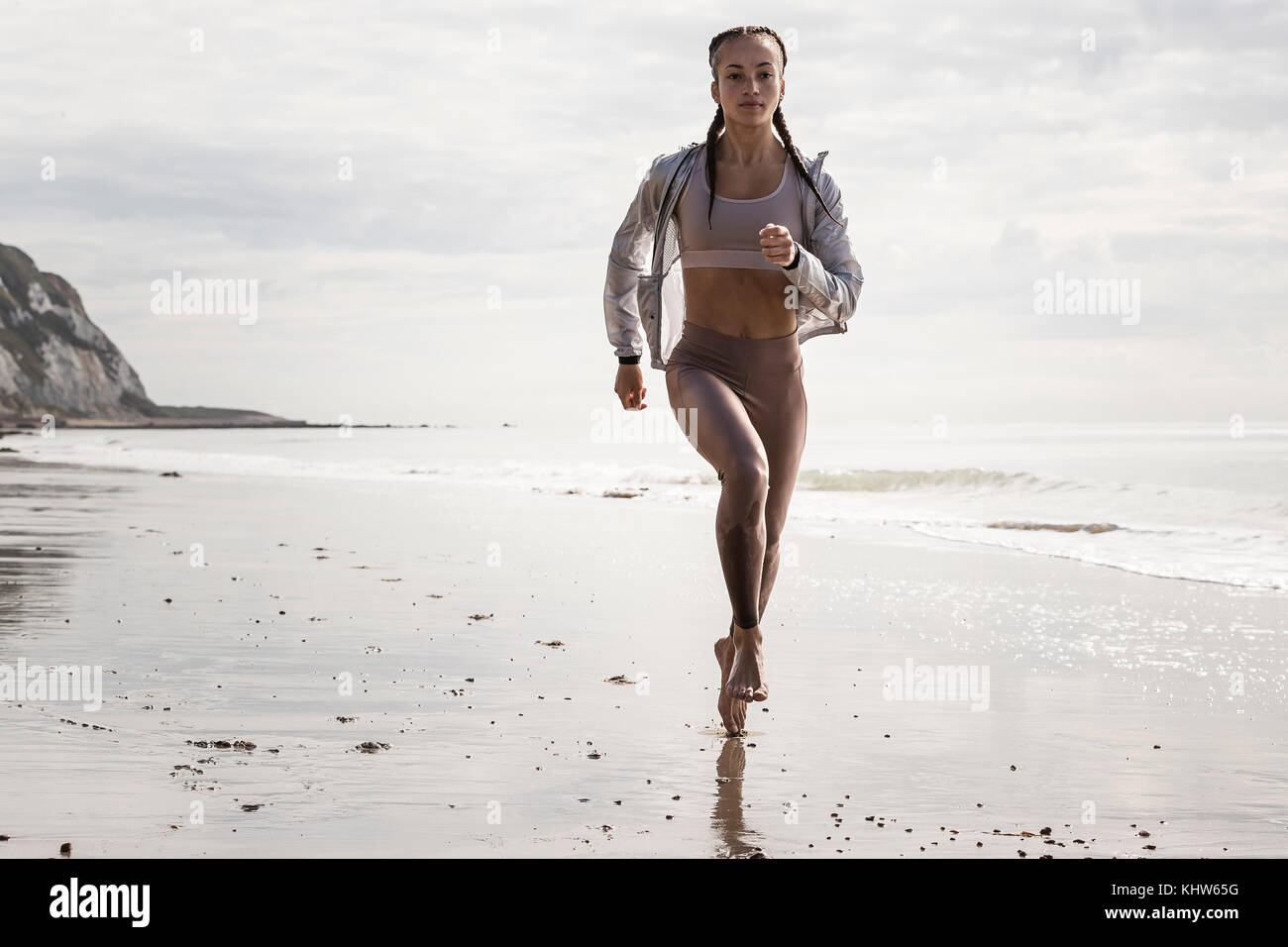 Vorderansicht des jungen weiblichen Läufer laufen barfuß am Strand Stockfoto