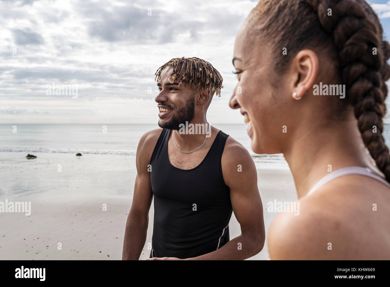 Junge männliche und weibliche Läufer Lächeln am Strand Stockfoto