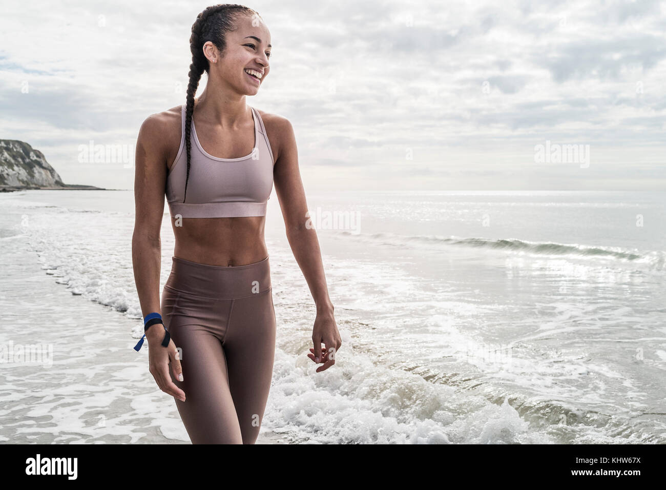 Junge Frau zu Fuß im Meer, Lächeln Stockfoto