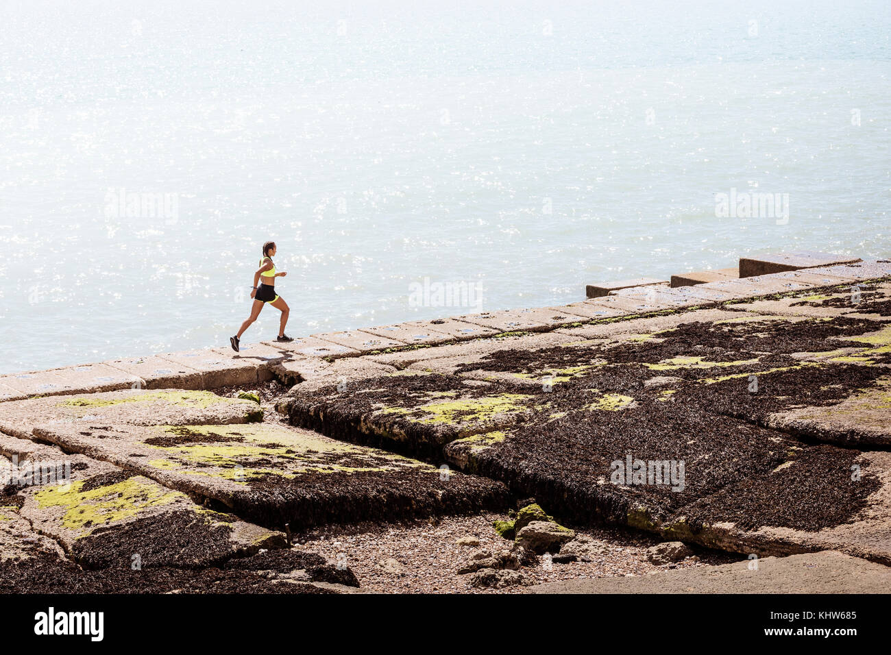 Junge Frau entlang Sea Wall läuft Stockfoto