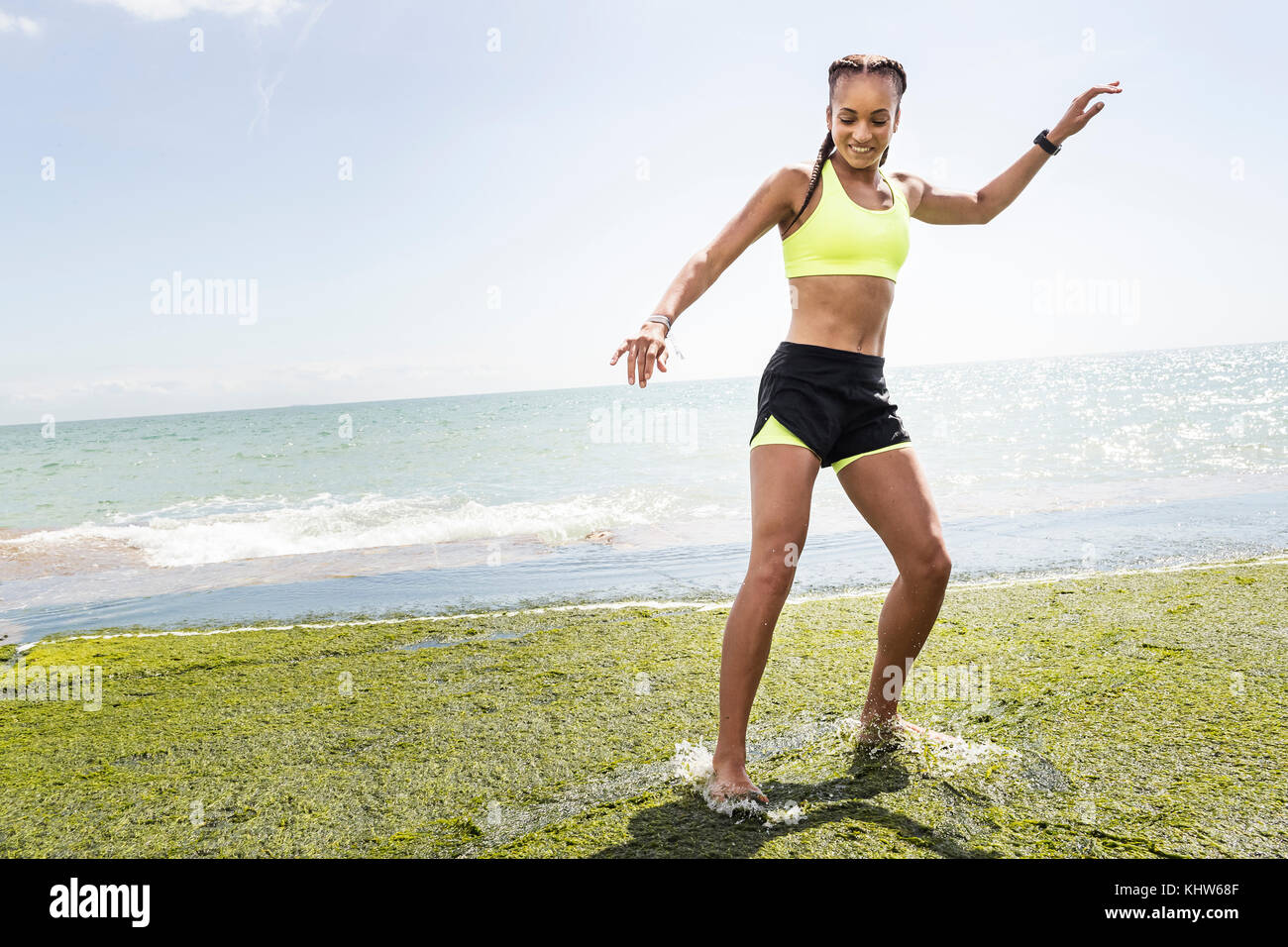 Junge Frau, barfuss auf Felsen, Plantschen im Wasser Stockfoto