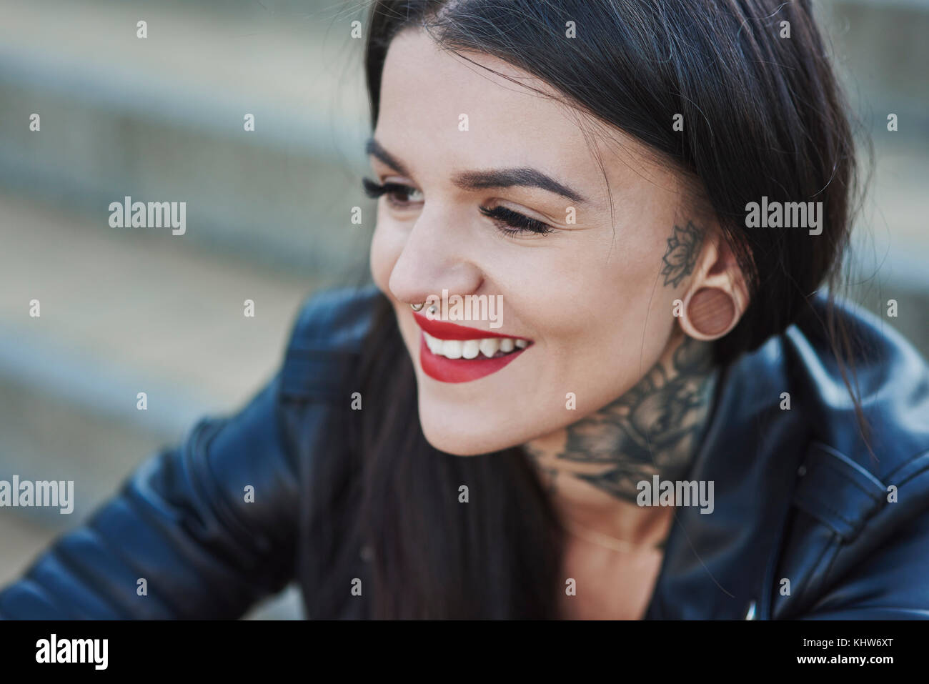 Porträt der jungen Frau lächelnd, Tattoos auf Hals, Nase und Ohr Piercings, close-up Stockfoto