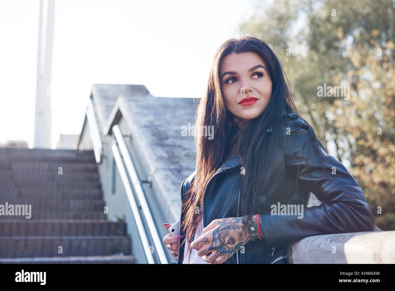 Portrait einer jungen Frau gegen die Wand lehnt, nachdenkliche Ausdruck, Tätowierungen an Hand Stockfoto