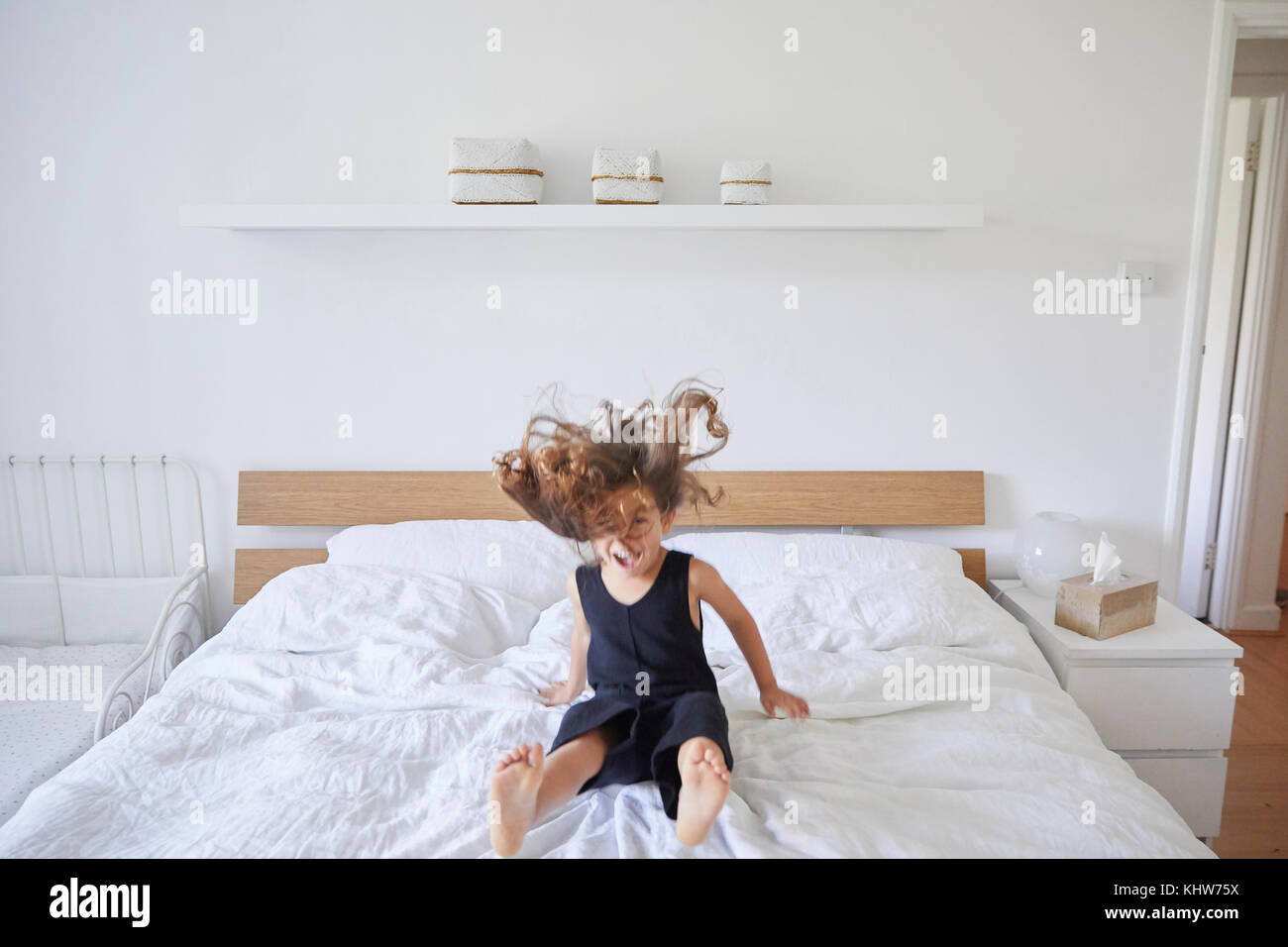 Junge Mädchen auf dem Bett springen Stockfoto