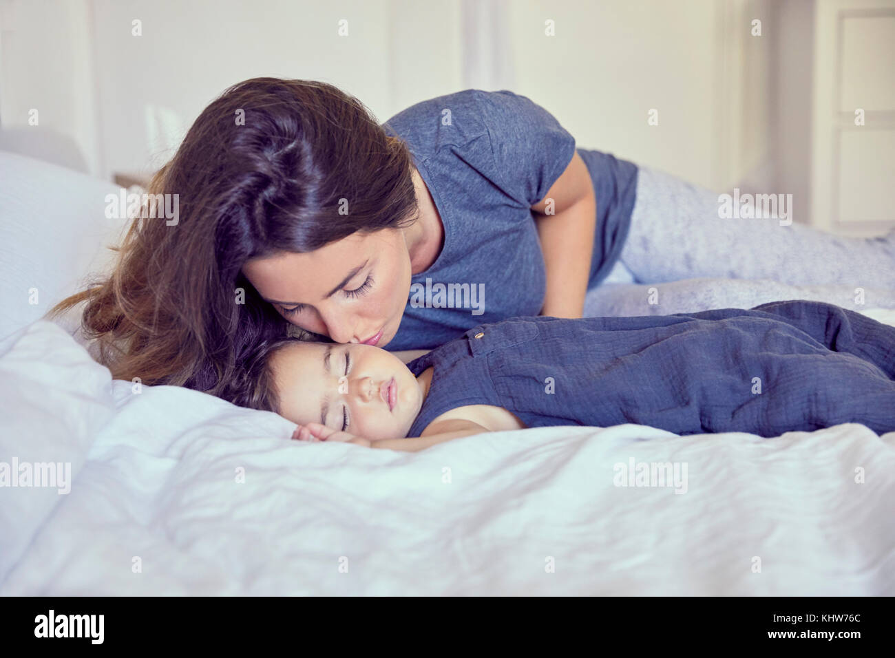 Mutter Witze schlafenden Kleinkind auf die Wange Stockfoto
