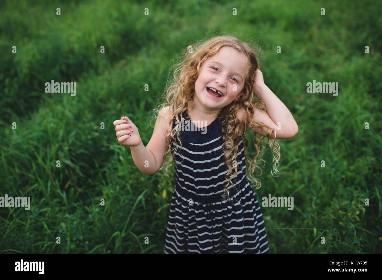 Mädchen, die an der Kamera auf der grünen Wiese Stockfoto